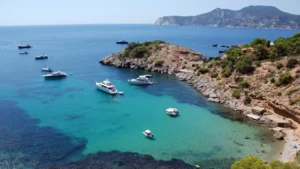 Cala Porroig en Ibiza con embarcaciones fondeadas y costa rocosa mediterránea.