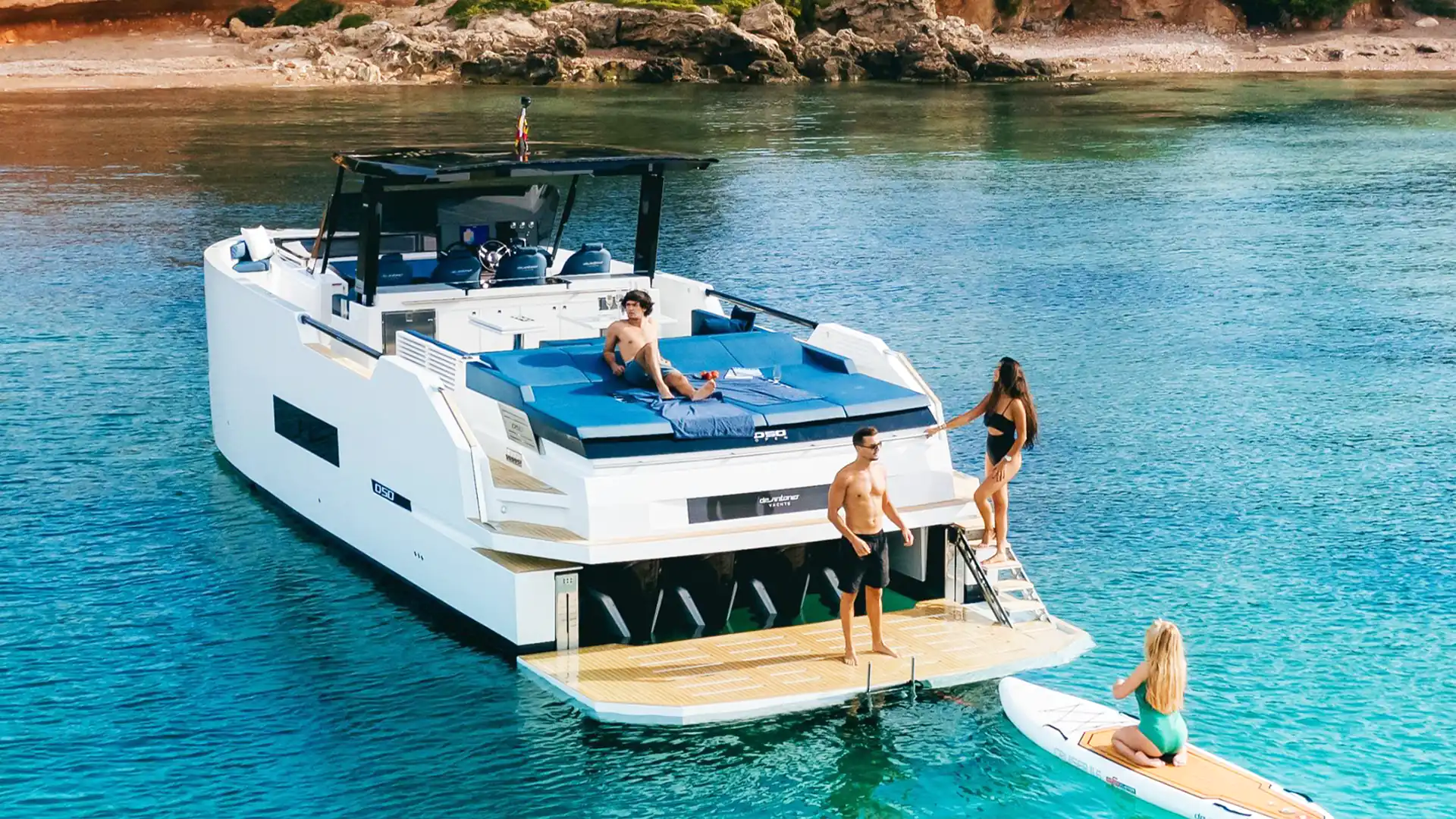Embarcación fondeada en Ibiza con plataforma de baño y pasajeros disfrutando a bordo