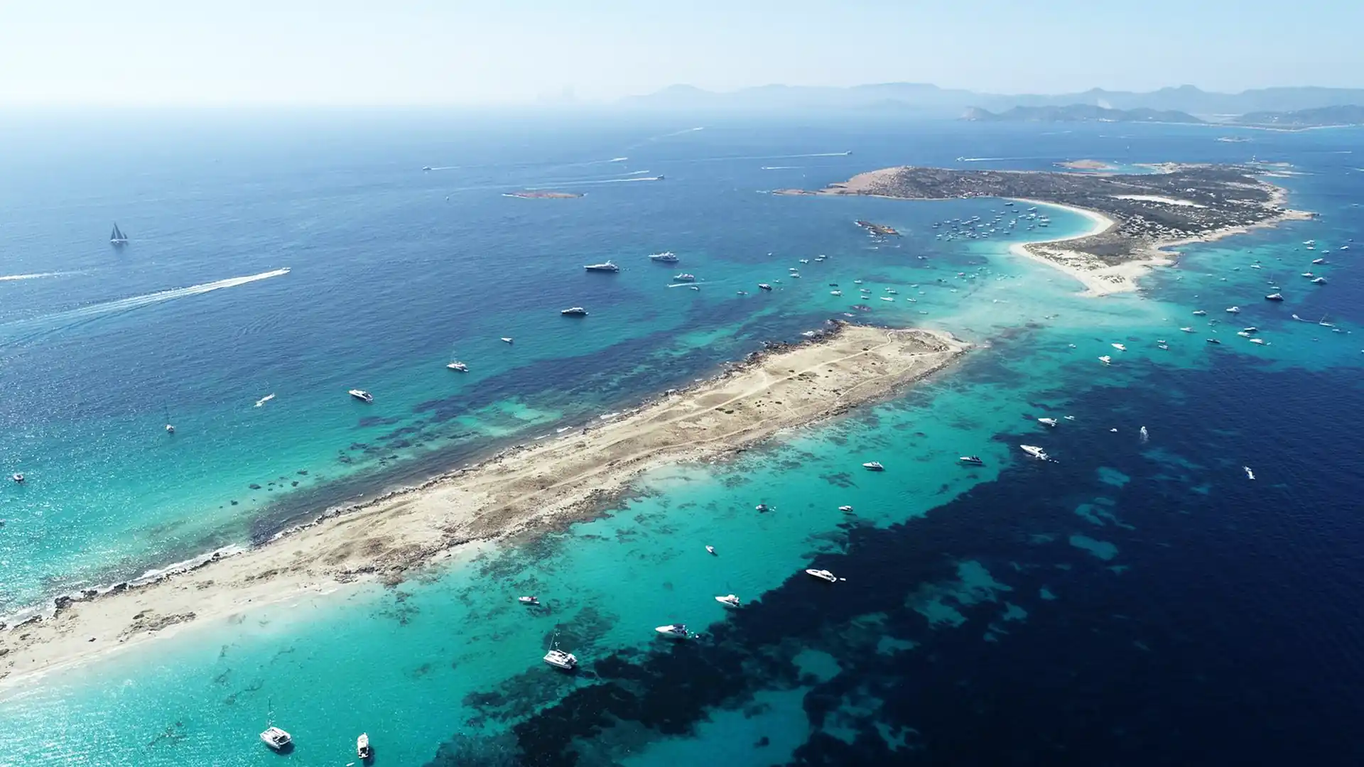 Vista aérea de El Paso en la costa levante de Formentera, con su lengua de arena y barcos fondeados sobre aguas turquesas