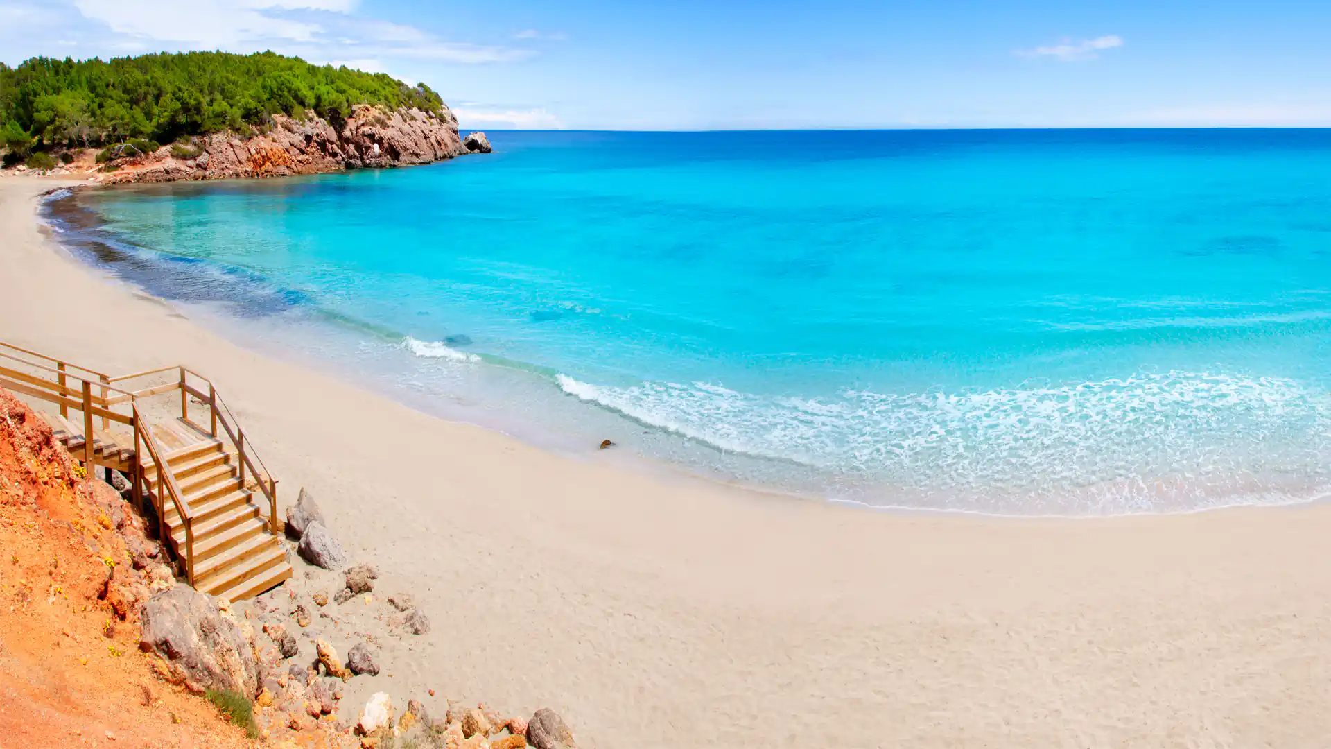 Playa de Cala Nova en el norte de Ibiza con aguas turquesas y acceso por escaleras de madera